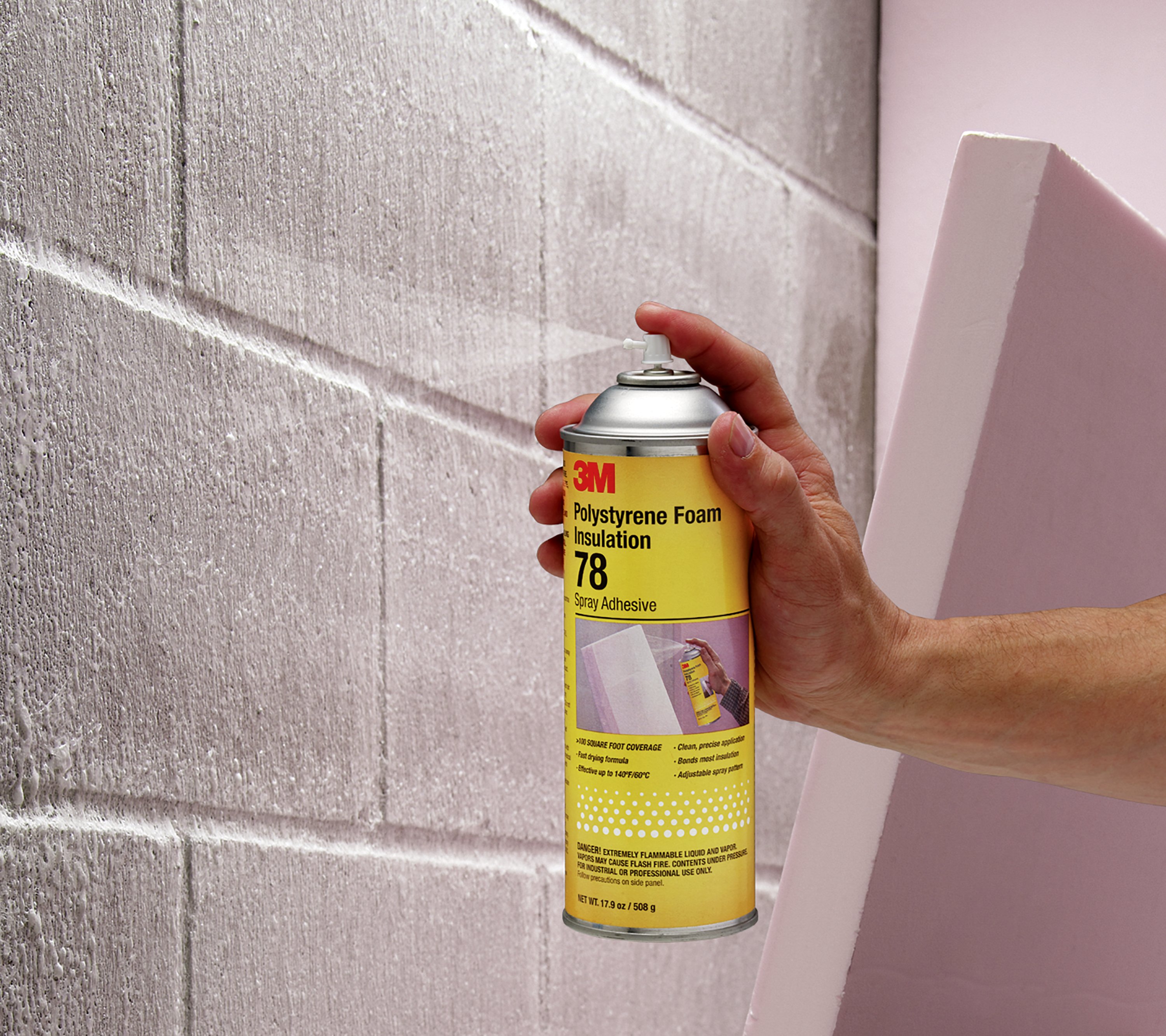 User spraying a concrete wall before applying polystyrene
